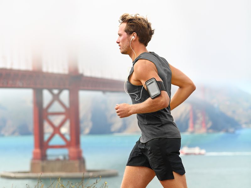 man running below bridge with music