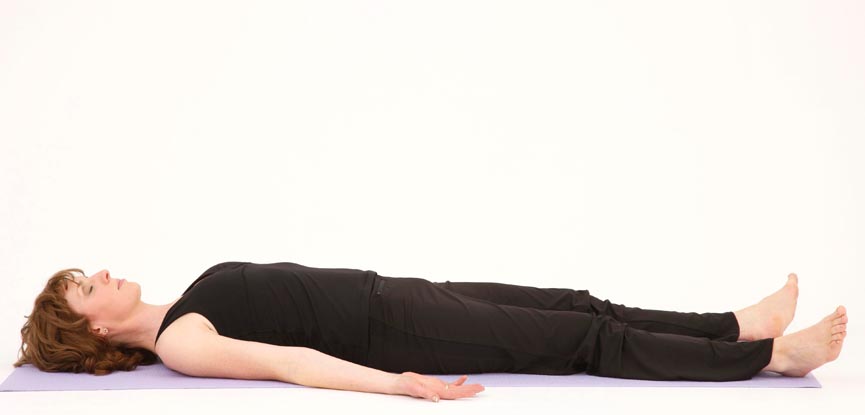 A yoga teacher performing a corpse pose