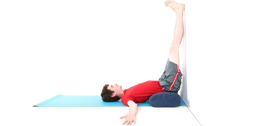 A male yoga instructor performing the legs up the wall pose