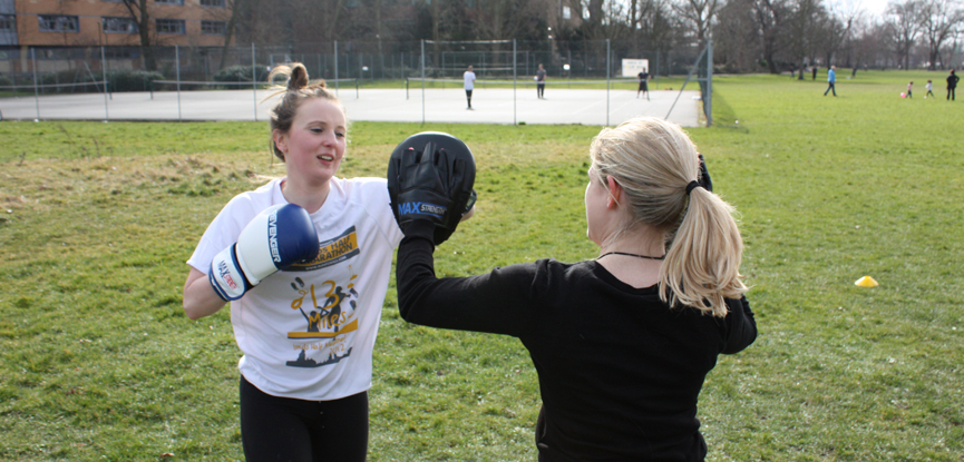 Boxing with a client at an outdoor personal training bootcamp