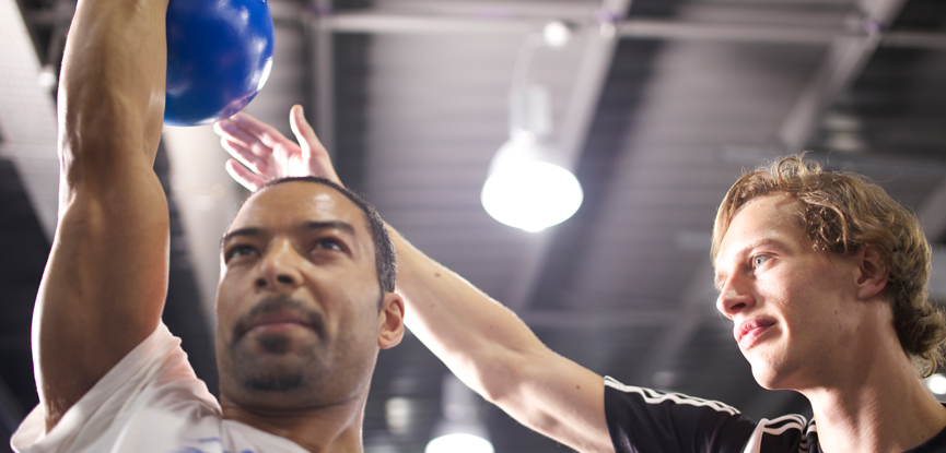 A personal trainer working with a client using a kettlebell