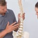 Back pain specialist showing a model of a spine to a client
