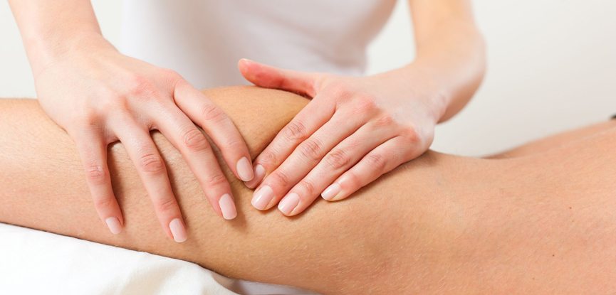 sports massage therapist's hands massaging client's leg