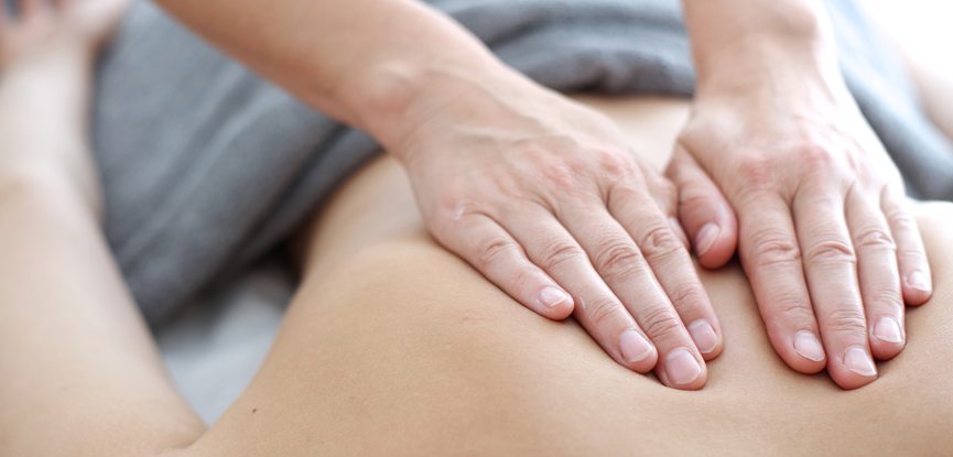 massage therapist's hands on client's back performing massage