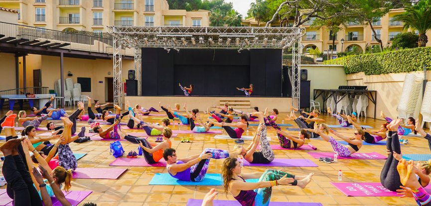 many yoga students following directions on stage at yoga retreat