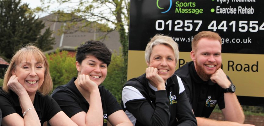 four sports massage therapists smiling at camera in SB sports massage rehabilitation branded t-shirts