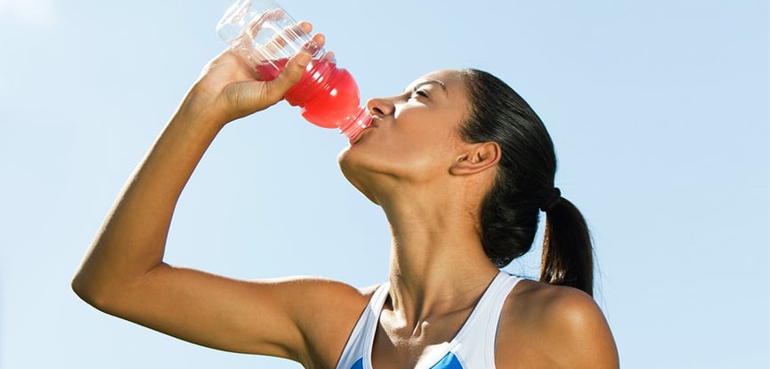 woman drinking from a bottle with a red coloured liquid.
