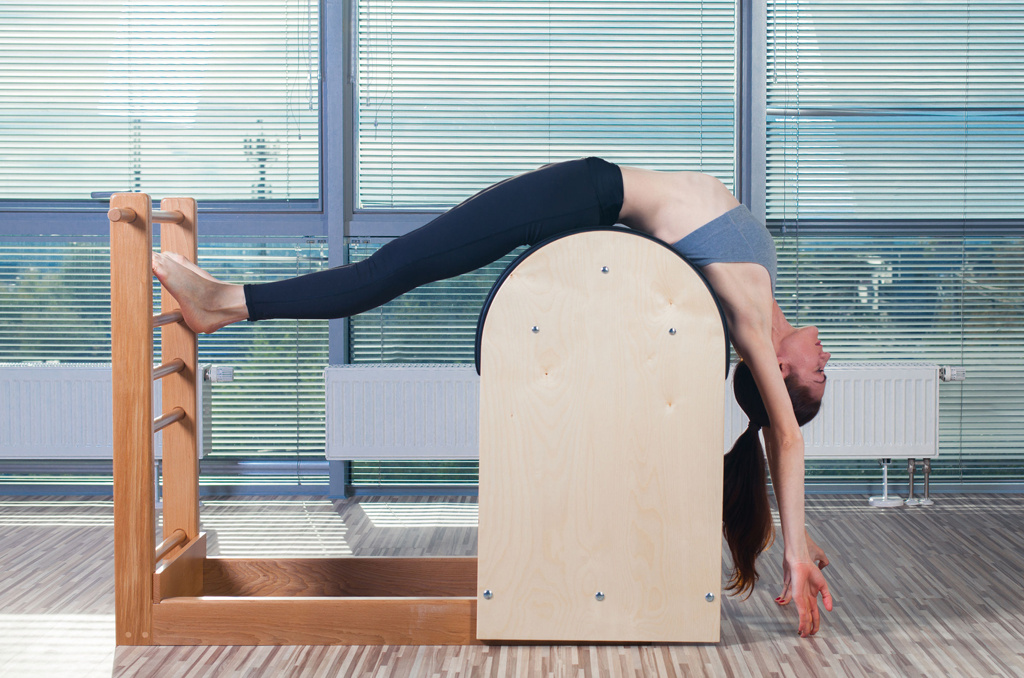 Female class participant using a ladder barrel in a Pilates class