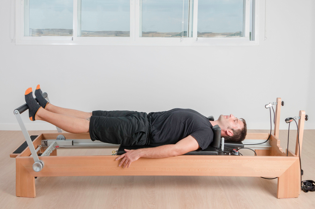 A class participant performing an exercise on a Pilates reformer