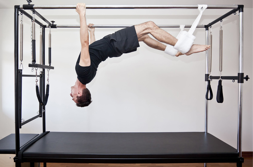 A man using the Trapeze, a specialised piece of Pilates equipment