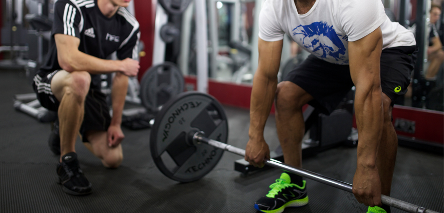 A personal trainer watching a client prepare for a deadlift