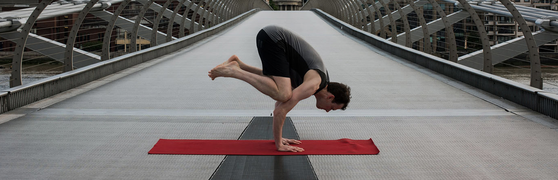 Scott Robinson, Yogibanker, performing crow pose on a bridge