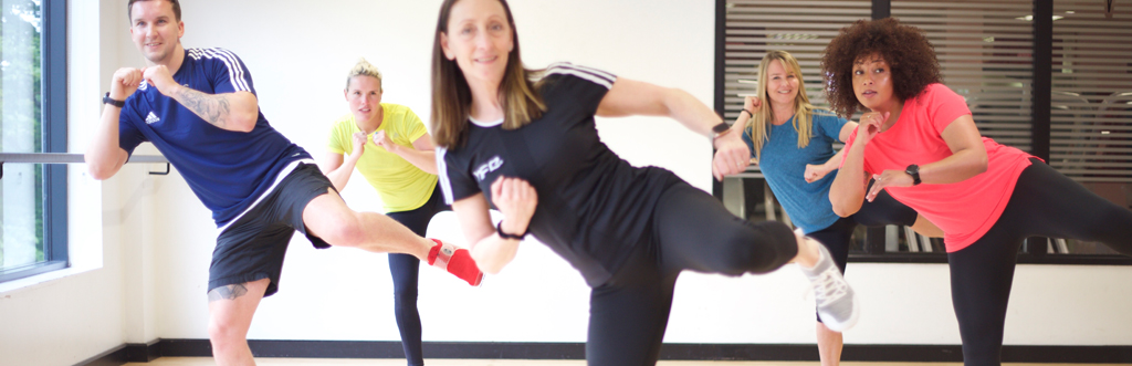 Exercise to music instructor performing a side kick