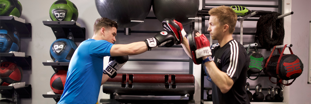 Personal trainer using boxing gloves and pads with a client