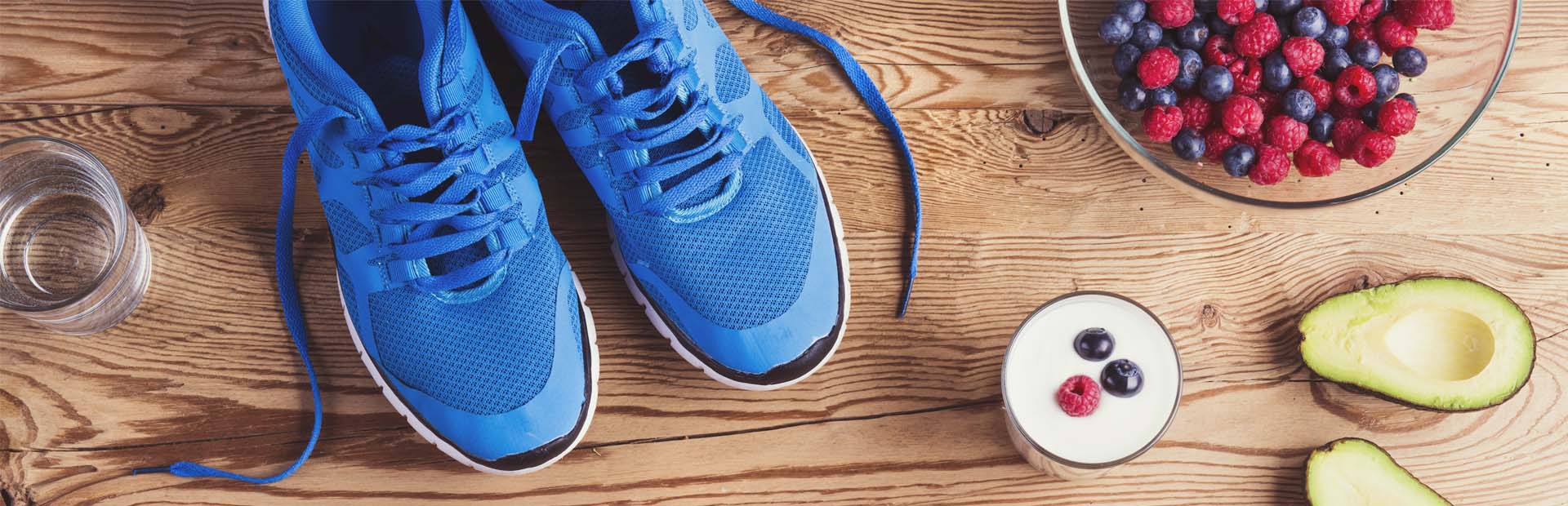 A pair of trainers beside various foods including berries and an avocado