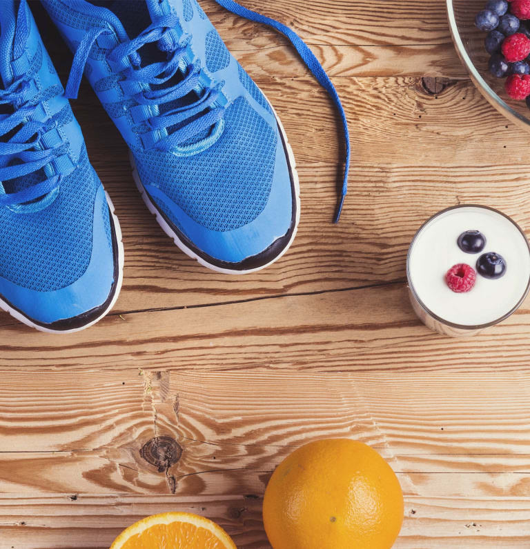 A pair of trainers beside various foods including berries and an orange