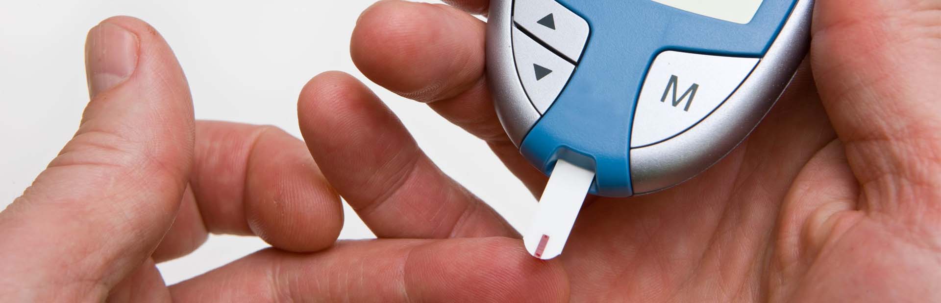 Person holding finger prick test to measure blood glucose for diabetes