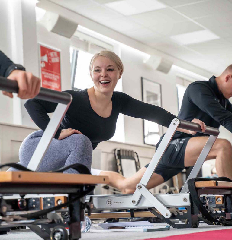 Pilates class member smiling on reformer