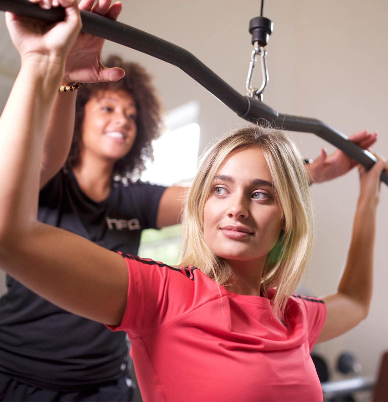 HFE gym instructor directing client on lat pulldown