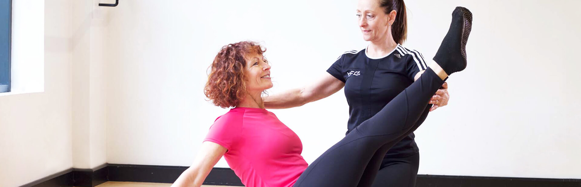 HFE Pilates instructor directing client on mat