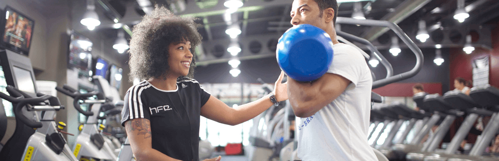 Personal trainer assisting client with kettlebell