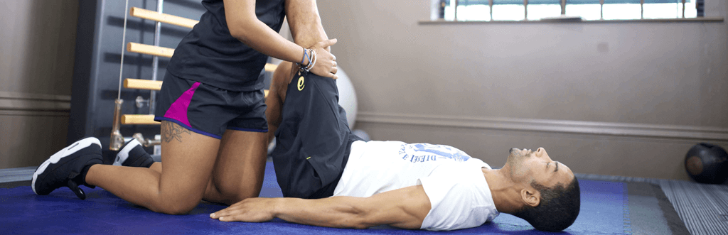 Personal trainer helping client stretch legs