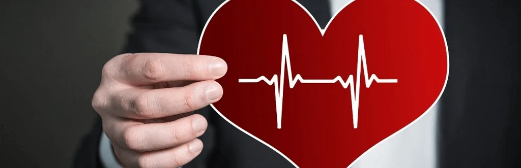 man holding cut out of a heart which shows heart rate