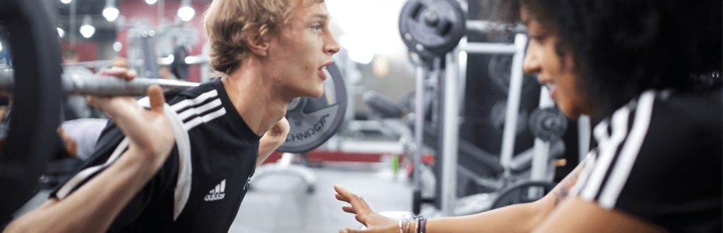 Man with personal trainer lifting weights