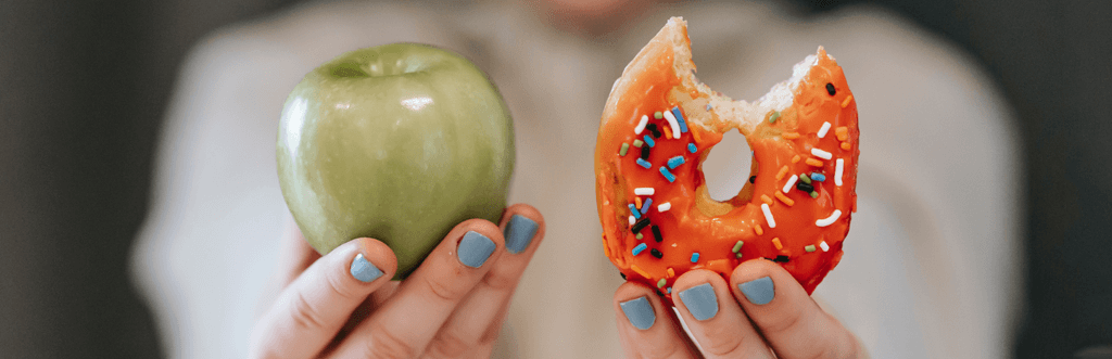 woman holding an apple and a doughnut