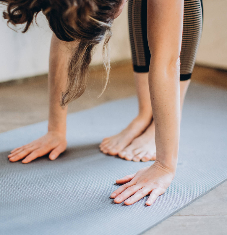 Woman completing a toe touch standing Pilates exercise