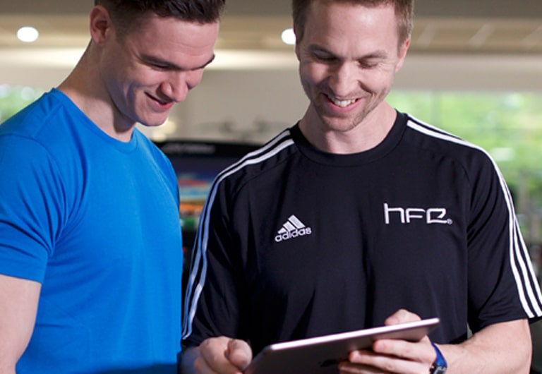 A personal trainer showing a client an app on an iPad tablet.