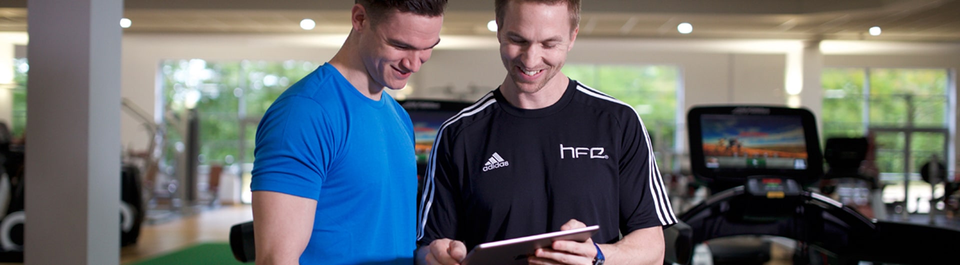 A personal trainer showing a client an app on an iPad tablet.
