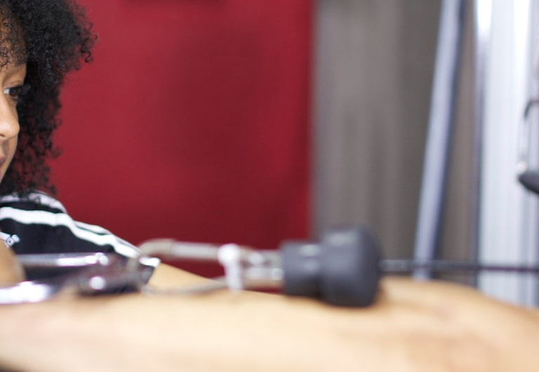 A HFE personal trainer guides a client through a cable exercise.