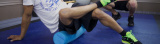 A person using a foam roller, guided by a personal trainer. A person using a foam roller, guided by a personal trainer.