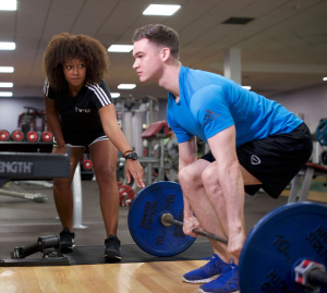 HFE Personal Trainer guides student through a deadlift.