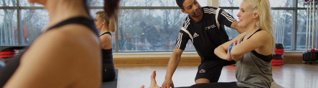 A HFE Pilates instructor guiding a class participant.
