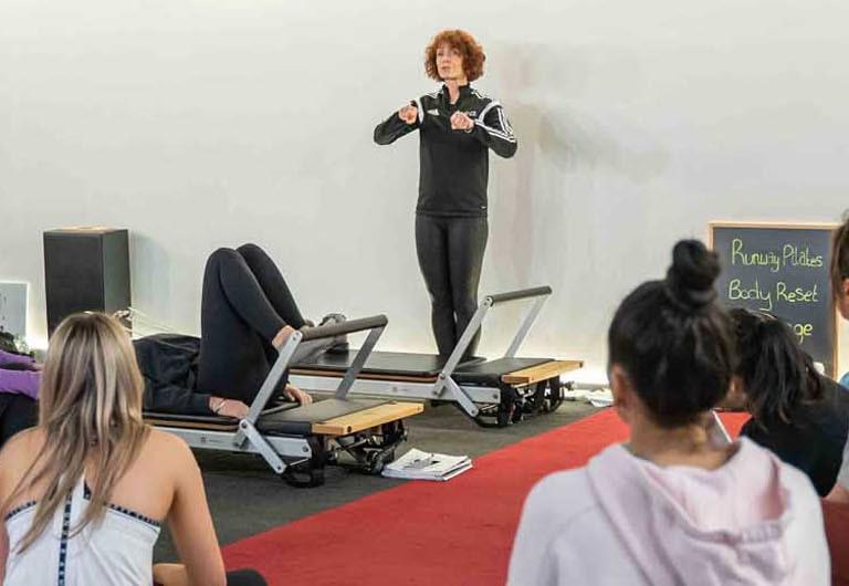 A HFE Pilates instructor talks to their reformer class.