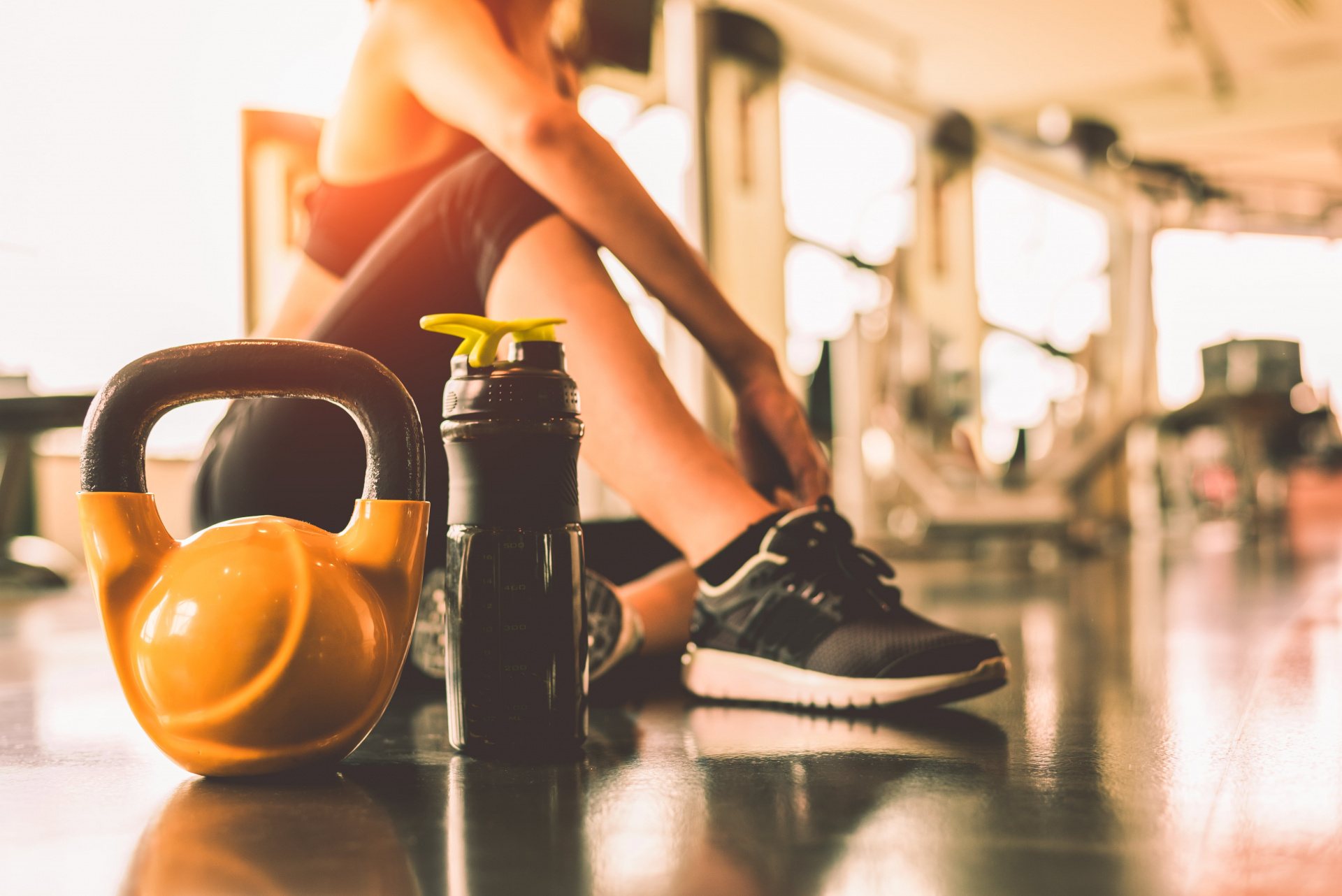 Woman resting next to kettlebell and bottle