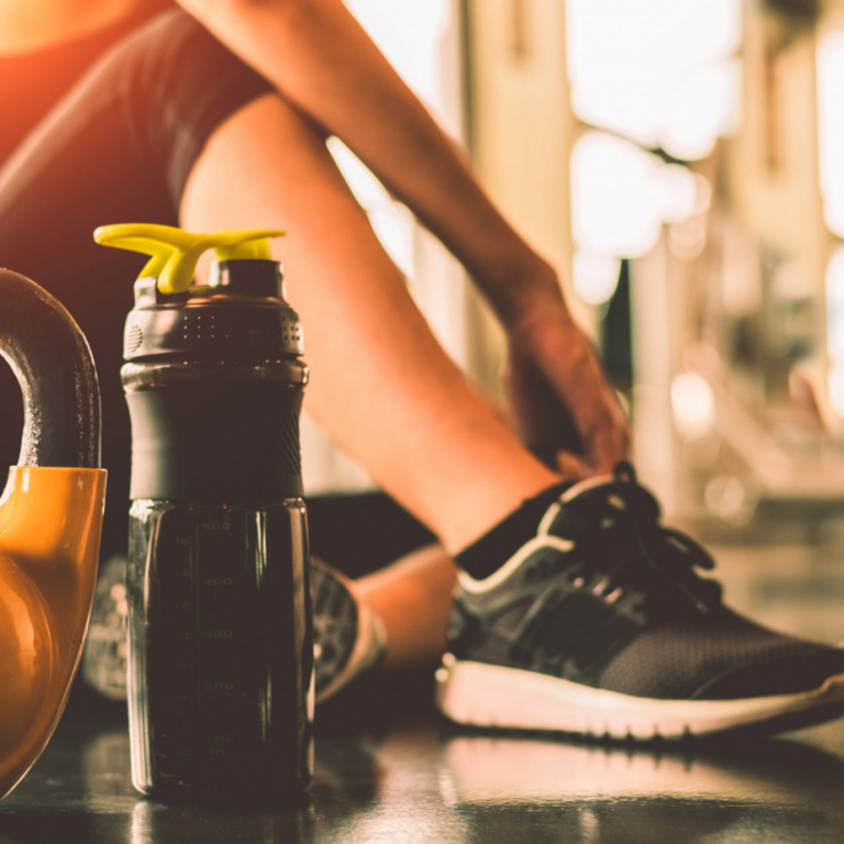 Woman resting next to kettlebell and bottle