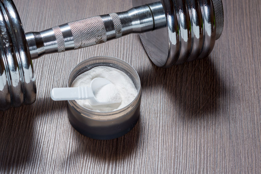 Creatine or protein powder with dumbbell
