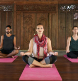 group of three performing Hatha yoga in temple