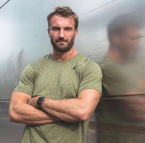 Luke Worthington looking at the camera with his arms crossed.