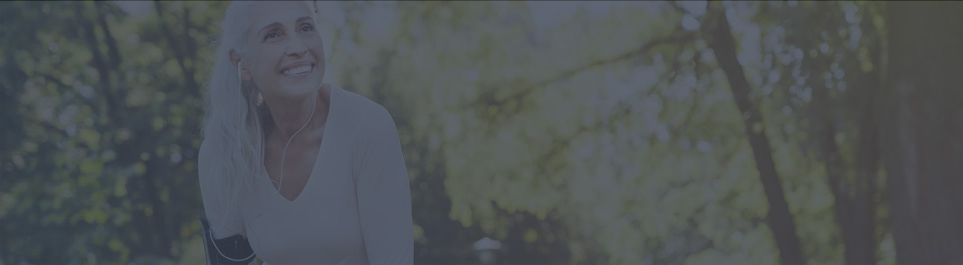 A woman smiling and listening to music while running through the woods A woman smiling and listening to music while running through the woods