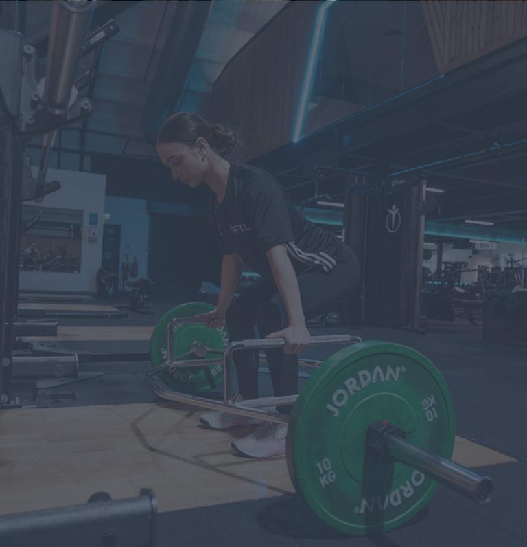 A female in a gym using the trap bar deadlift