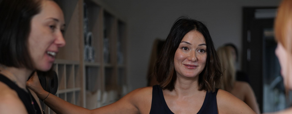 Three women in a Pilates studio talking to one another