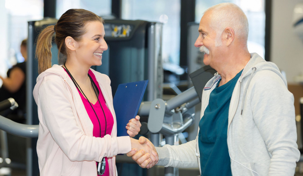 A personal trainer shaking the hand of her older adult client