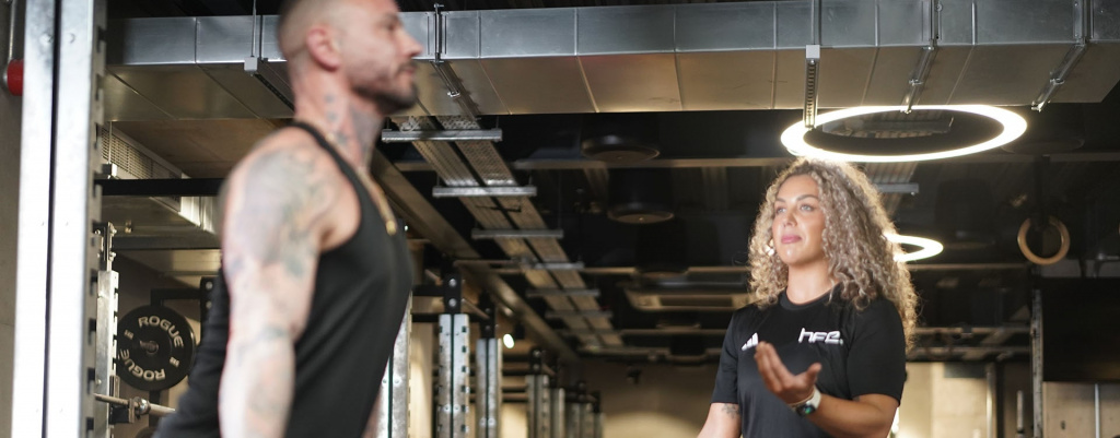 A female PT assisting a client with a deadlift