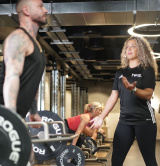 A female PT assisting a client with a deadlift