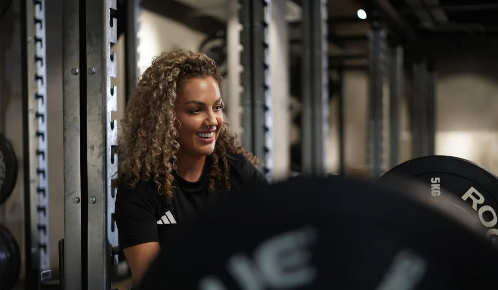 A personal trainer crouched by a deadlift in the gym A personal trainer crouched by a deadlift in the gym