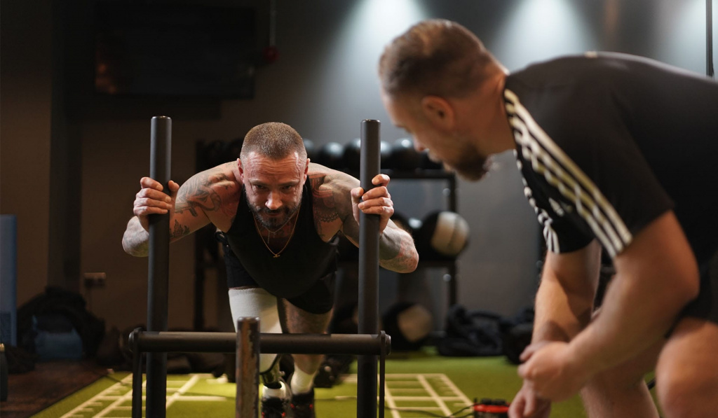 A personal trainer assisting a client pushing a prowler A personal trainer assisting a client pushing a prowler